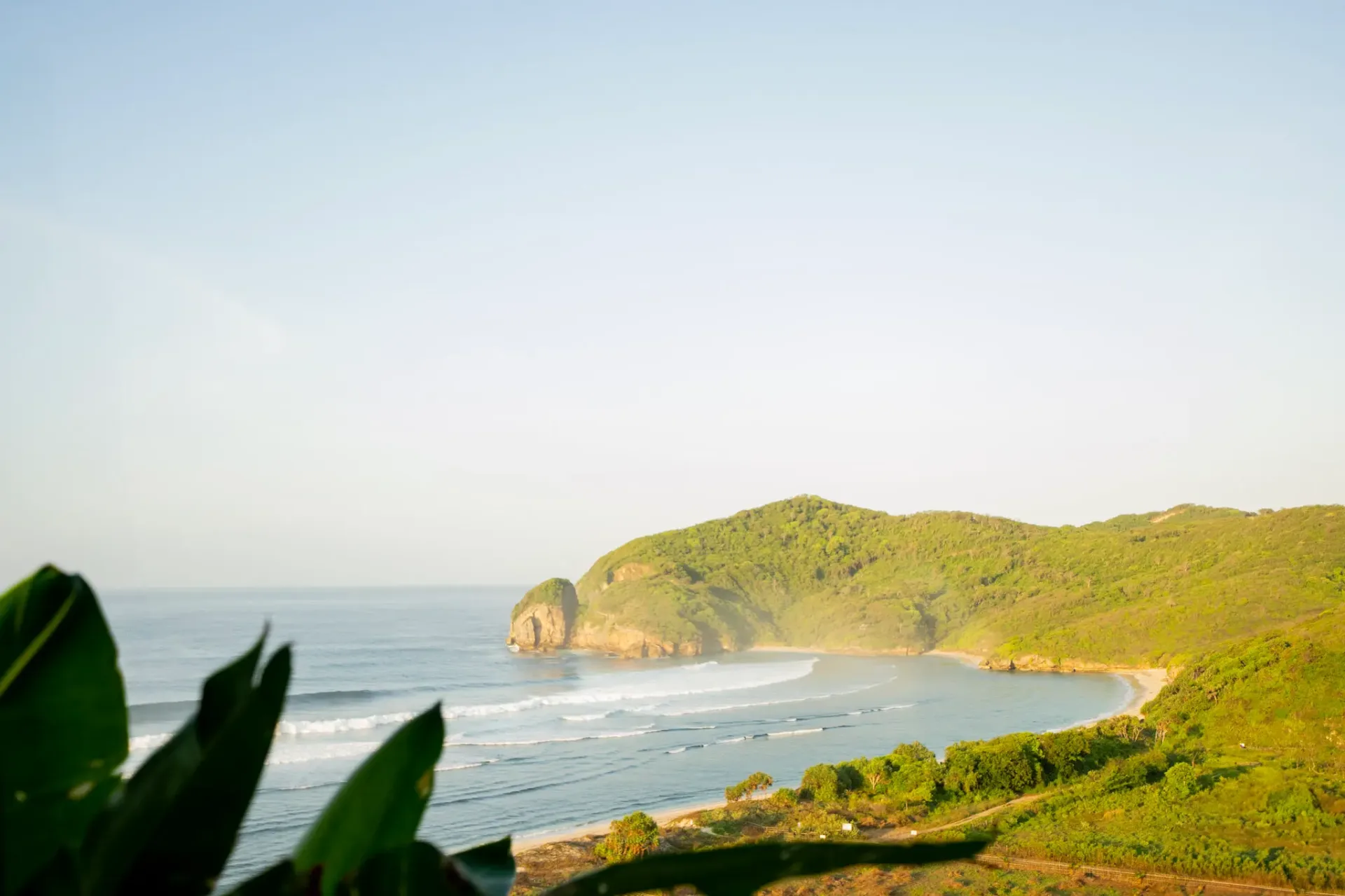 Aerial view of pristine coastline with lush green hills and ocean waves at Elysian Cove resort